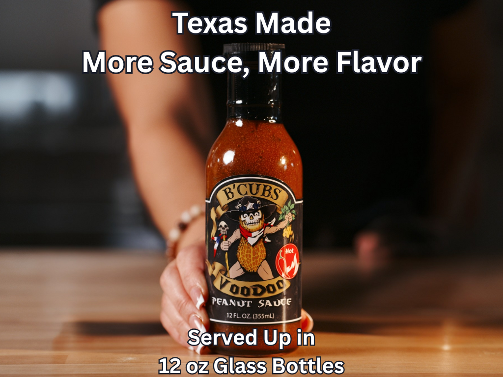 B'Cubs Voodoo Peanut Sauce bottle held by a person with text overlay on a wooden surface.